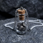Āgāya Rasam silver — macro of meteorite fragments in teardrop vial